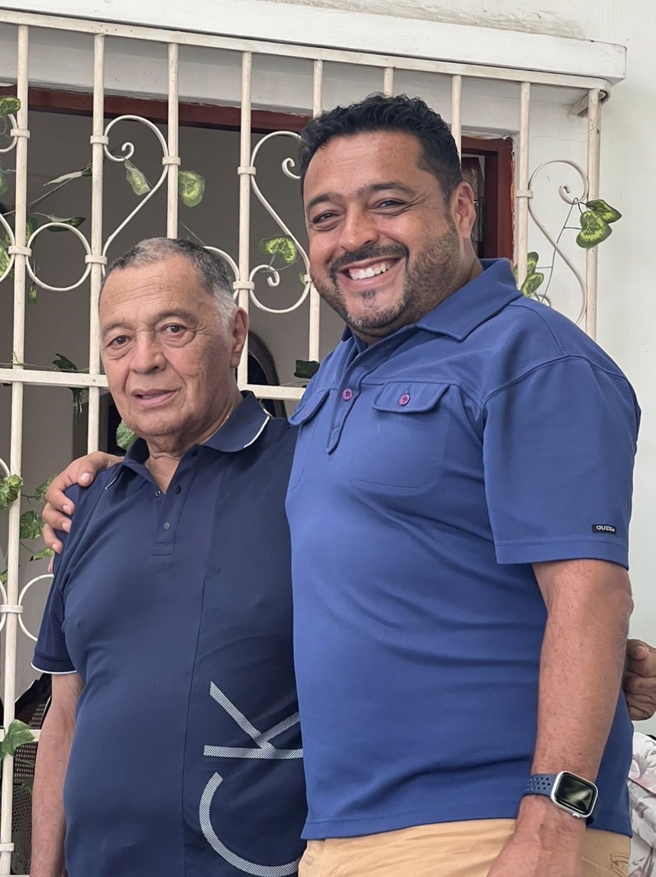Un hijo abraza a su papá mayor en la puerta de su casa